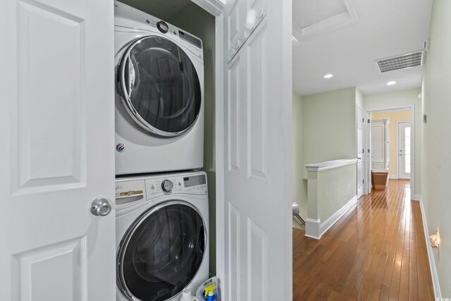 laundry room featuring wood-type flooring and stacked washing maching and dryer