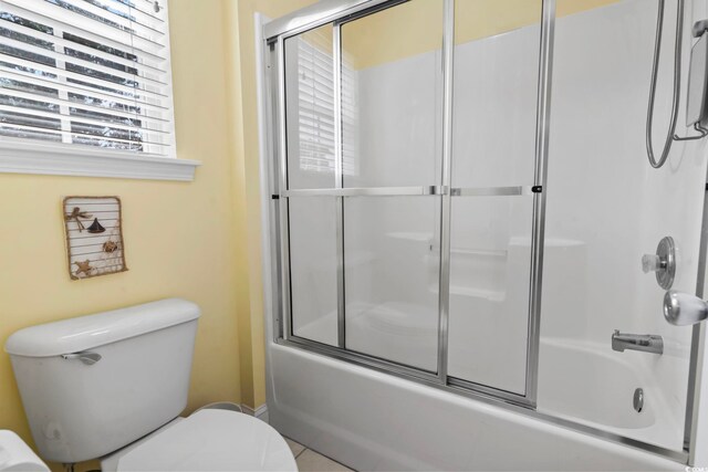 bathroom featuring tile patterned floors, enclosed tub / shower combo, and toilet