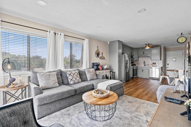 living area featuring ornamental molding, wood finished floors, and a ceiling fan