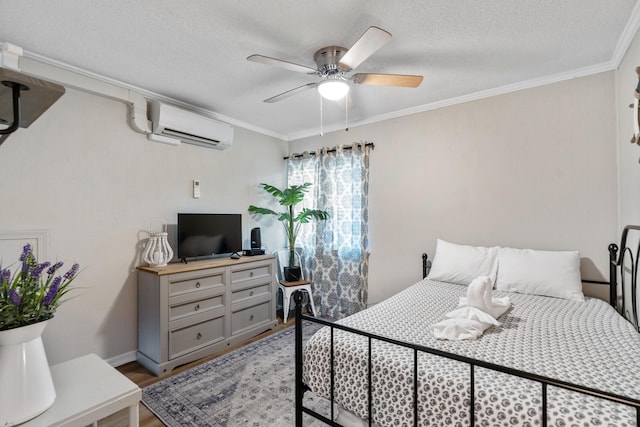 bedroom with a textured ceiling, ceiling fan, wood finished floors, a wall mounted air conditioner, and crown molding