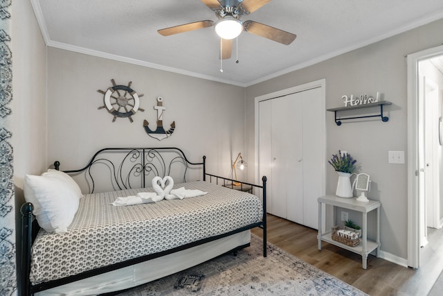 bedroom featuring baseboards, a ceiling fan, ornamental molding, wood finished floors, and a closet