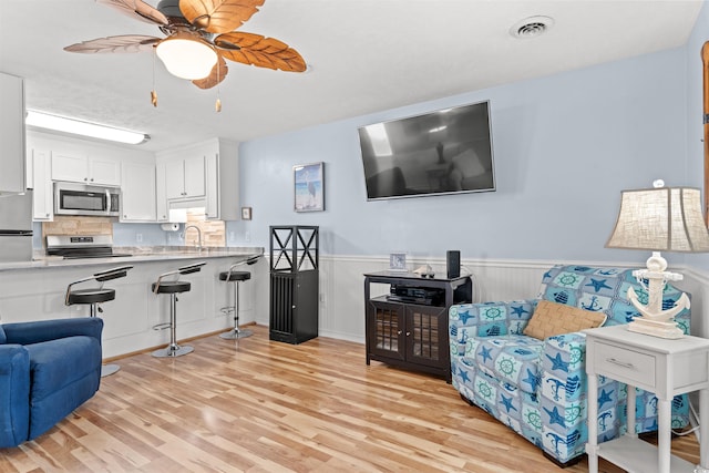 living room featuring sink, ceiling fan, and light wood-type flooring