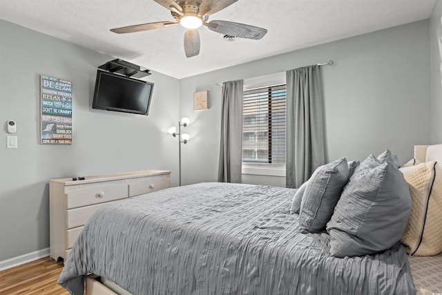 bedroom featuring ceiling fan, light hardwood / wood-style floors, and a textured ceiling