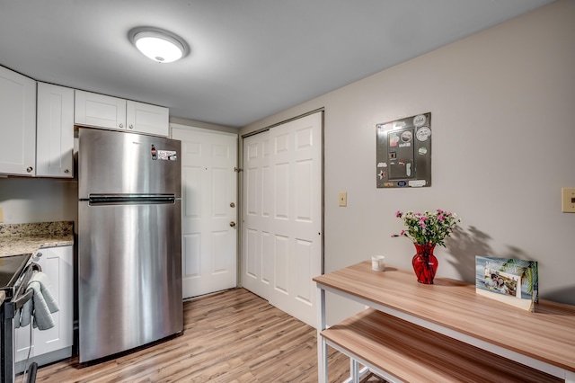 kitchen featuring stainless steel appliances, light wood-type flooring, white cabinetry, and light stone countertops