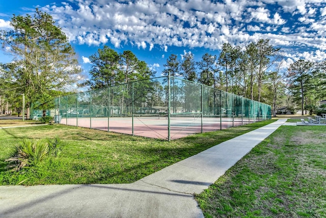 view of tennis court with a yard and fence