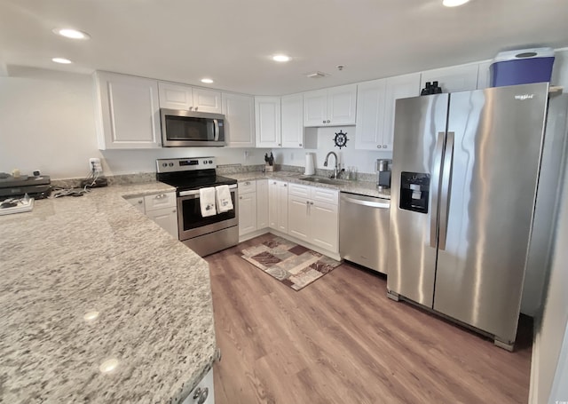 kitchen with white cabinetry, sink, light stone counters, and stainless steel appliances