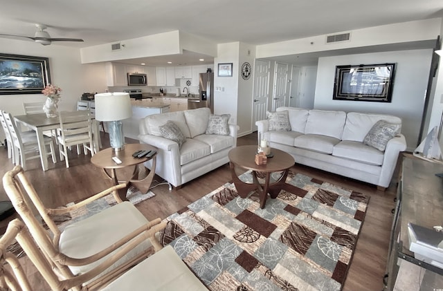 living room featuring dark hardwood / wood-style floors, sink, and ceiling fan