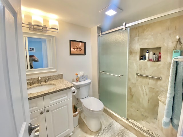 bathroom with vanity, toilet, and a shower with door