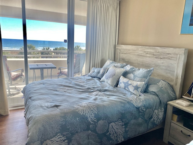 bedroom with hardwood / wood-style flooring, a water view, and access to outside