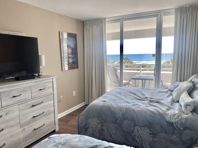 bedroom with dark hardwood / wood-style floors, a view of the beach, access to exterior, floor to ceiling windows, and a water view