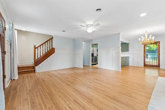 unfurnished living room featuring ceiling fan with notable chandelier, light wood-type flooring, and ornamental molding