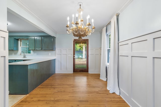 kitchen with pendant lighting, green cabinetry, a notable chandelier, crown molding, and light hardwood / wood-style floors