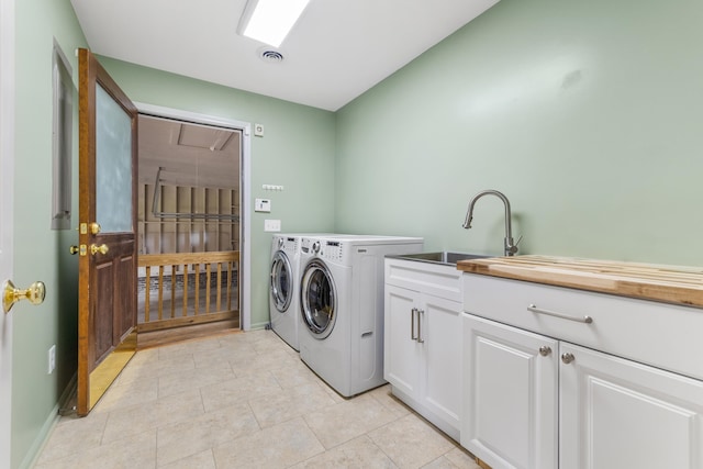 laundry area with washer and clothes dryer, sink, light tile patterned floors, and cabinets