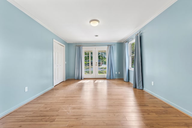 empty room featuring french doors, light wood-type flooring, and crown molding