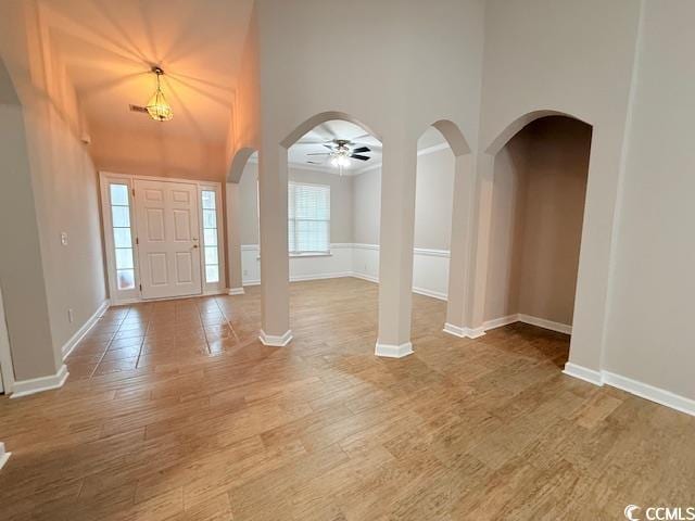 entrance foyer with hardwood / wood-style floors, a towering ceiling, and ceiling fan