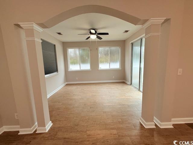 unfurnished room with light hardwood / wood-style flooring, ceiling fan, and ornate columns