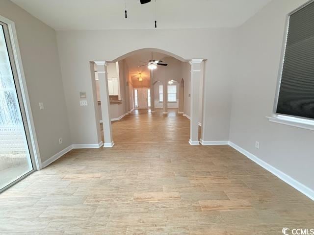 unfurnished room with ceiling fan, decorative columns, and light wood-type flooring