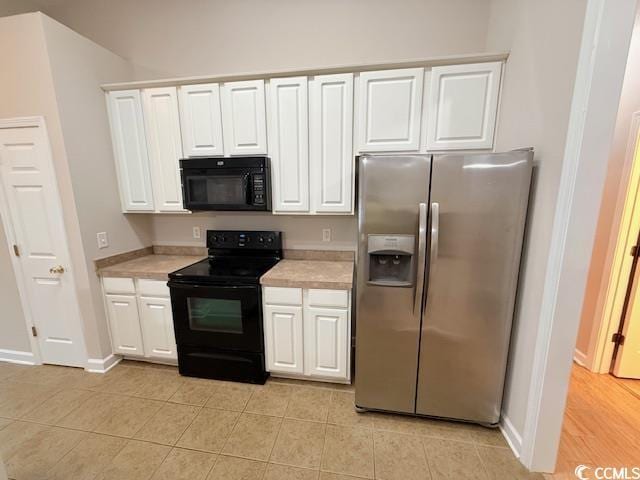 kitchen featuring white cabinetry, light tile patterned flooring, and black appliances