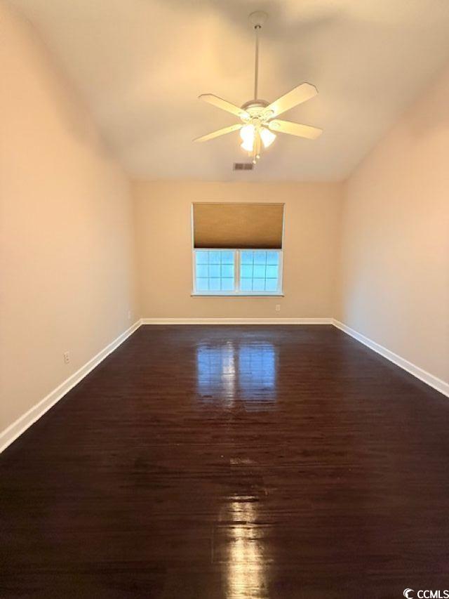 empty room with ceiling fan, dark hardwood / wood-style flooring, and vaulted ceiling