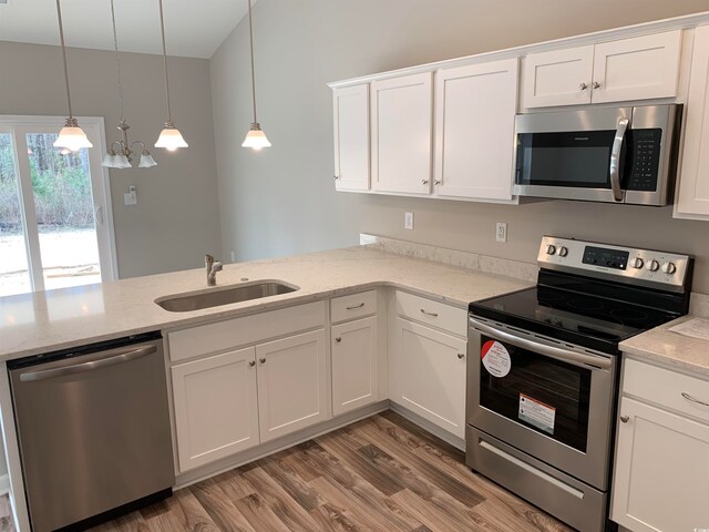 kitchen featuring white cabinetry, hardwood / wood-style flooring, stainless steel appliances, and pendant lighting