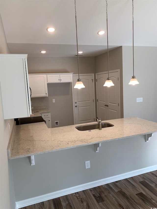 kitchen with kitchen peninsula, decorative light fixtures, white cabinets, and sink