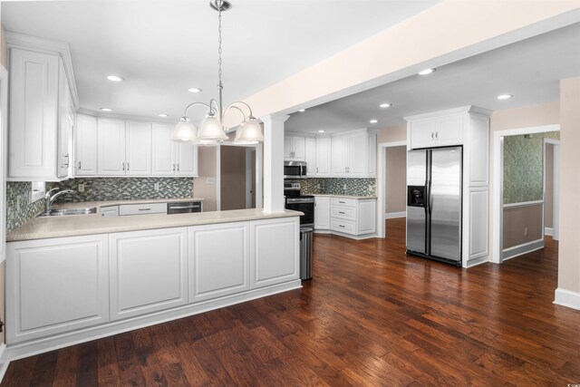 kitchen with white cabinets, appliances with stainless steel finishes, dark hardwood / wood-style floors, pendant lighting, and sink