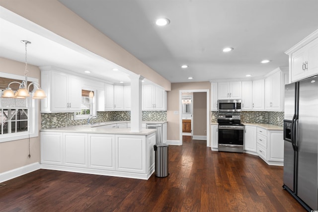 kitchen with appliances with stainless steel finishes, pendant lighting, white cabinetry, and dark hardwood / wood-style flooring