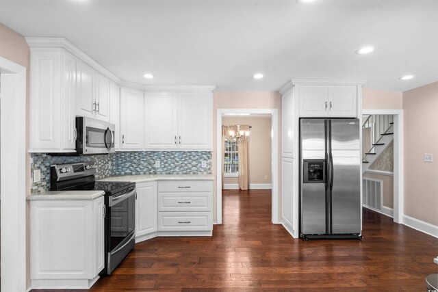 kitchen with white cabinets, backsplash, an inviting chandelier, dark wood-type flooring, and stainless steel appliances