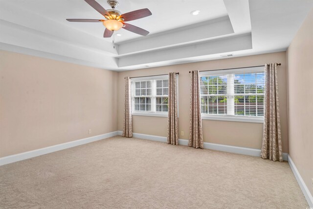 carpeted empty room with ceiling fan and a tray ceiling