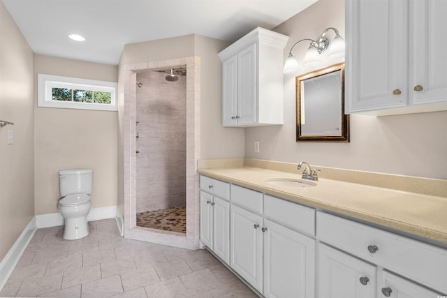 bathroom featuring vanity, a tile shower, toilet, and tile patterned floors