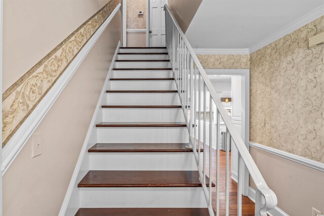 staircase with hardwood / wood-style floors and crown molding