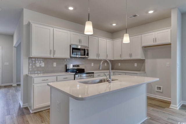 kitchen with a kitchen island with sink, white cabinetry, and stainless steel appliances