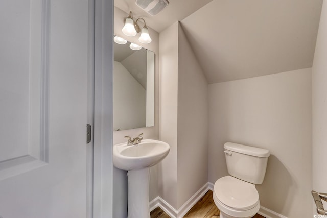 bathroom featuring toilet, wood-type flooring, vaulted ceiling, and sink