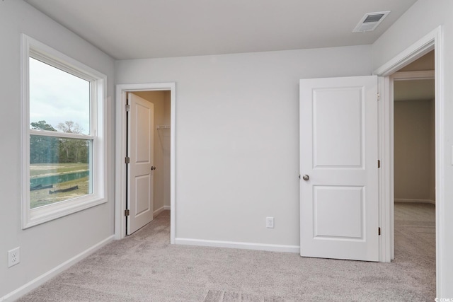 unfurnished bedroom with light colored carpet, a spacious closet, and a closet