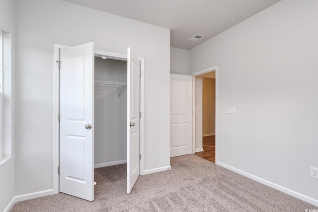 unfurnished bedroom with light colored carpet and a closet