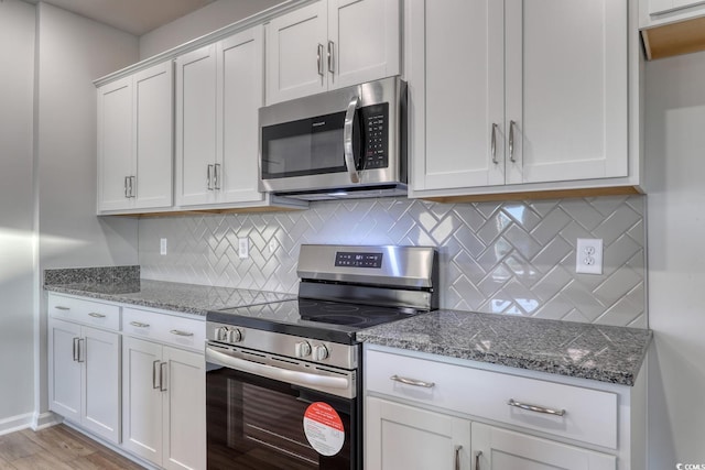 kitchen featuring backsplash, stone counters, light hardwood / wood-style floors, white cabinetry, and stainless steel appliances