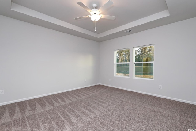 carpeted empty room with ceiling fan and a tray ceiling