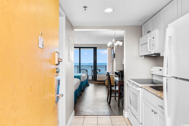 kitchen featuring white cabinets, a water view, a notable chandelier, and white appliances