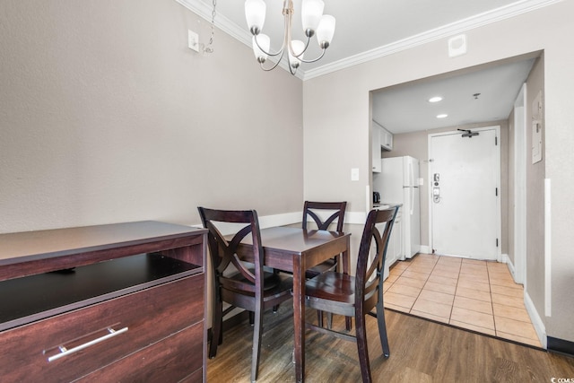 dining room featuring ornamental molding, light wood-type flooring, and a notable chandelier