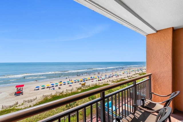 balcony with a water view and a view of the beach