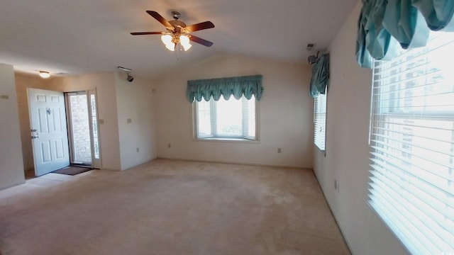 empty room with lofted ceiling, ceiling fan, and light colored carpet