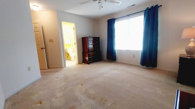 unfurnished bedroom featuring ensuite bathroom, light colored carpet, and ceiling fan