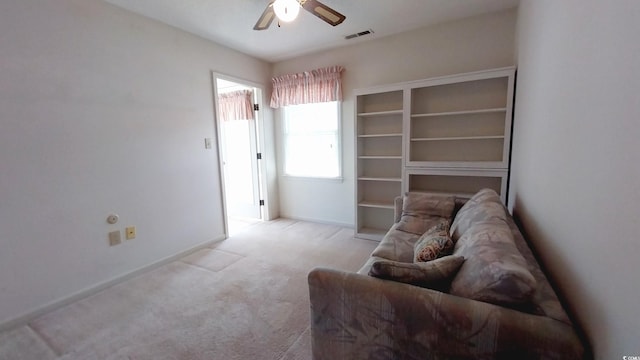 living area featuring light carpet and ceiling fan