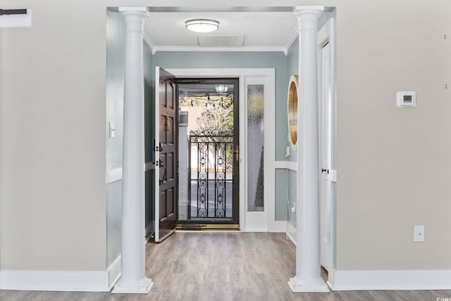 entryway with decorative columns, ornamental molding, and light wood-type flooring