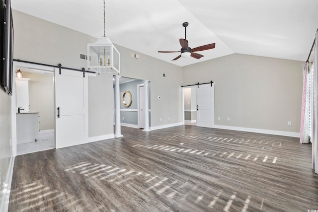 unfurnished living room with dark wood-type flooring, ceiling fan, lofted ceiling, and a barn door