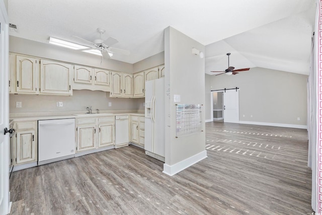 kitchen with white appliances, lofted ceiling, sink, light hardwood / wood-style flooring, and a barn door