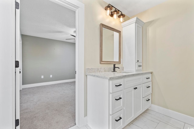 bathroom with ceiling fan, vanity, and a textured ceiling