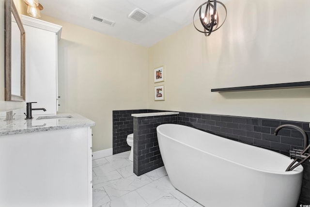 bathroom featuring a bath, toilet, an inviting chandelier, and vanity