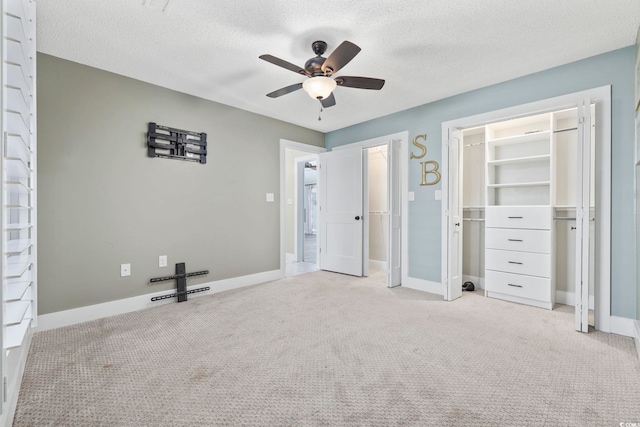 unfurnished bedroom featuring ceiling fan, a textured ceiling, a closet, and light carpet