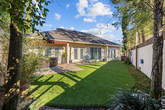 back of house with a lawn, a hot tub, and a patio